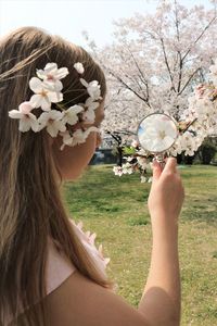 Portrait of woman holding cherry blossom by tree