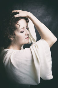 Side view of young woman looking away against black background