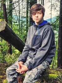 Full length of boy sitting in forest