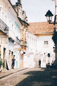 People walking on street amidst buildings in city