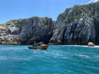 Sailboat on rock by sea against blue sky