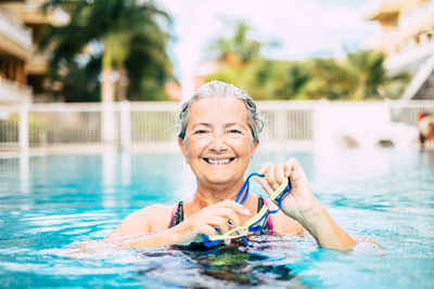 Portrait of smiling senior woman swimming in pool
