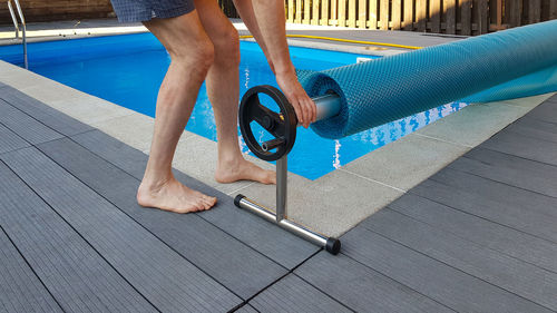 Low section of man standing on footpath by swimming pool