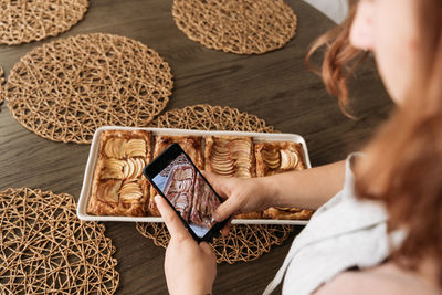 Female hands taking pictures of apple tart with mobile phone