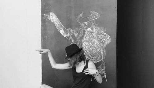 Young woman standing against drawing on blackboard