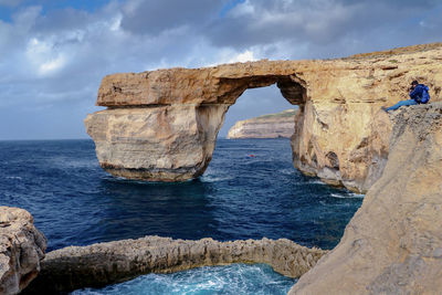 Scenic view of rock formation in sea against sky