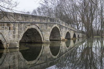 Arch bridge over river against sky