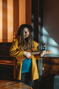 Young woman holding guitar at home