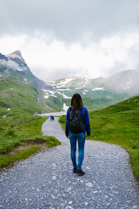 Rear view of woman walking on mountain against sky