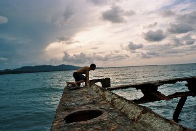 Pier on sea against cloudy sky
