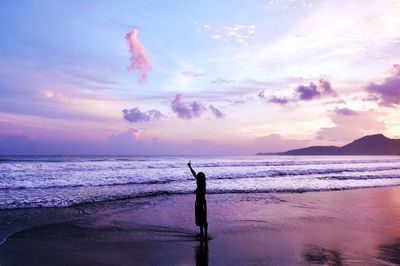 Man standing on beach against sky during sunset