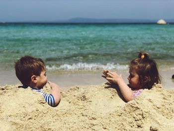Playful children in sand at beach during summer