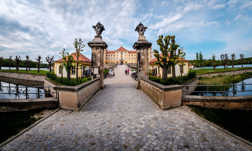 Statue by historic building against sky