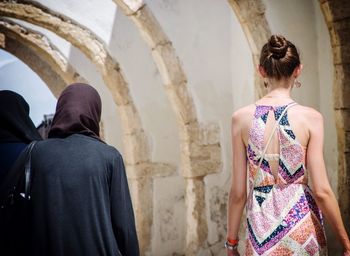 Rear of woman wearing sleeveless dress and two women wearing hijab