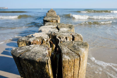 Wooden posts in sea on sunny day