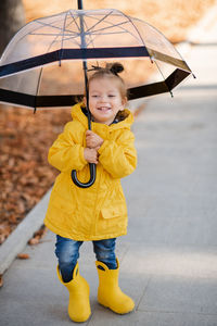 Portrait of boy with umbrella standing on road