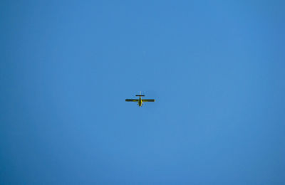 Low angle view of airplane flying in clear blue sky