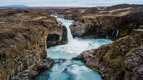 Scenic view of waterfall against sky