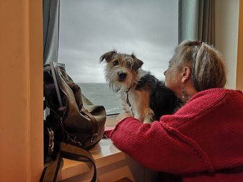 Rear view of woman with dog sitting at home