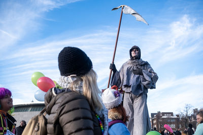 Low angle view of people on street against sky