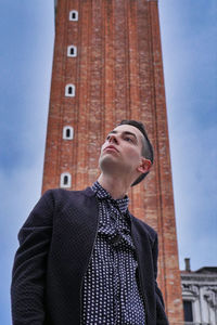 Low angle view of man looking away against building