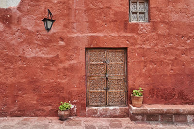 Spanish colonial building with rich red color on the facade, and antique wooden door with ornaments