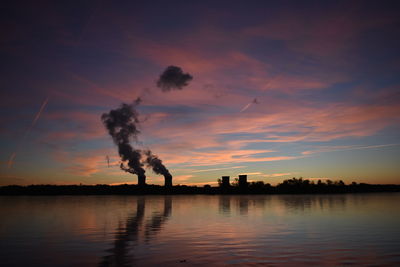 Smoke emitting from factory against sky during sunset