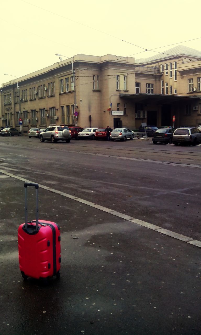 transportation, car, building exterior, land vehicle, mode of transport, street, architecture, built structure, city, road, parking, red, stationary, city street, outdoors, parked, building, day, traffic, no people