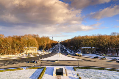 Road by trees against sky during winter