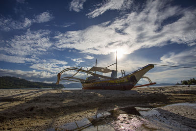 Abandoned boat on beach against sky