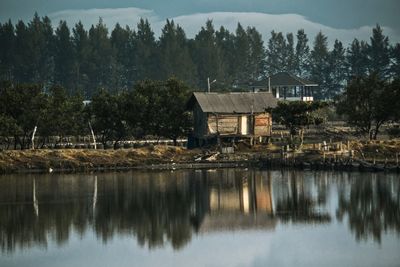 House by lake and trees against mountain