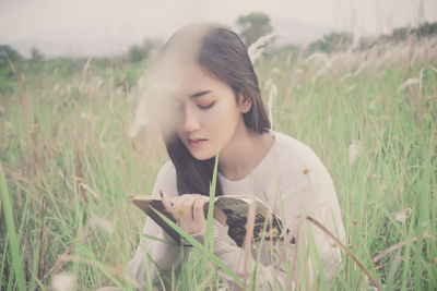 Young woman reading book while sitting on grass