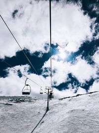 Ski lift over snowcapped mountains against sky