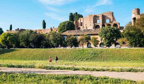 Field by old buildings in circus maximus against clear sky