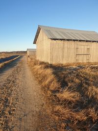 Abandoned building on field against clear blue sky