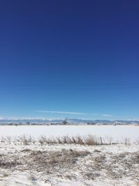 Snow covered landscape against blue sky