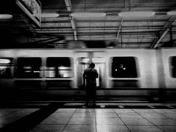 Rear view of woman standing at railroad station