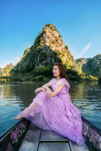 Portrait of young woman sitting on pier over lake