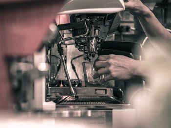Cropped hands of barista making coffee in machinery