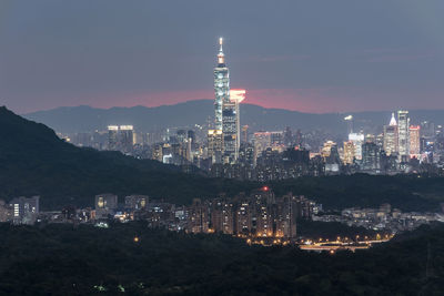 Illuminated buildings in city against sky at night