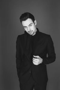 Portrait of young man standing against gray background