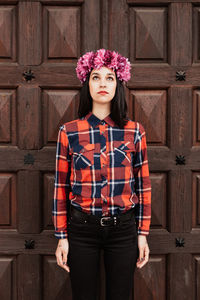 Portrait of young woman standing against wall