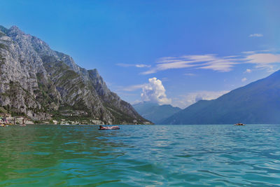 Teenage boy floating on lake against blue sky