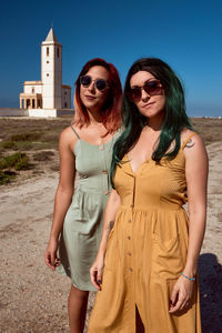 Young woman wearing sunglasses standing against the sky