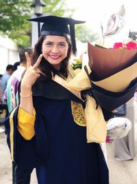Portrait of smiling woman in graduation gown gesturing