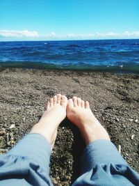 Low section of woman on beach against sky