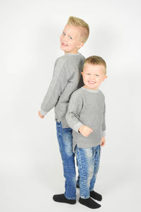 Portrait of twin brothers standing against white background