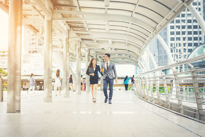 Businesswoman with colleague walking on elevated walkway in city