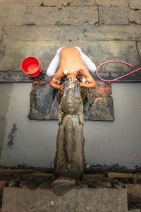 High angle view of man bathing from water fountain at temple