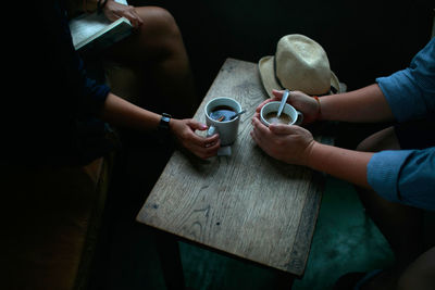 Midsection of woman holding coffee while sitting on table